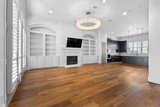 1156 Mosaico Ln, Houston, TX 77055 - unfurnished living room featuring crown molding, hardwood / wood-style flooring, a fireplace with flush hearth, recessed lighting, and built in features