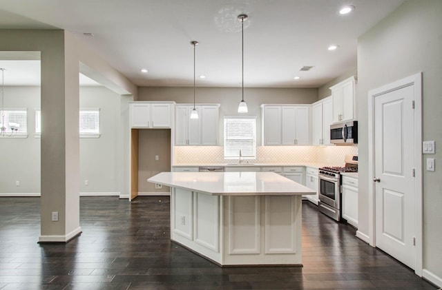 6914 N Elmwood Trl, Katy, TX 77493 - kitchen with appliances with stainless steel finishes, a center island, decorative backsplash, white cabinetry, and dark wood-type flooring