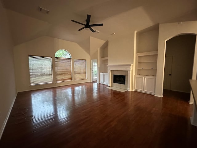 2606 Iris Ct, Pearland, TX 77584 - unfurnished living room featuring arched walkways, built in features, a ceiling fan, wood finished floors, and a tiled fireplace