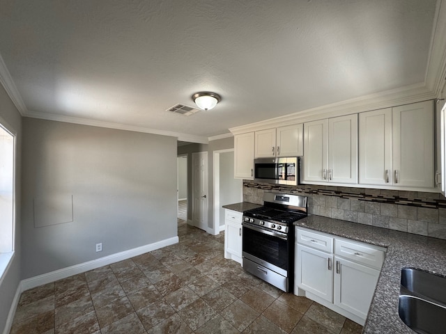 1013 E 40th St, Houston, TX 77022 - kitchen with appliances with stainless steel finishes, dark countertops, backsplash, ornamental molding, and white cabinetry