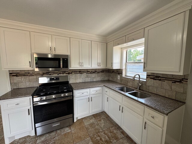 1013 E 40th St, Houston, TX 77022 - kitchen featuring stainless steel appliances, backsplash, white cabinetry, dark stone finish floors, and dark stone countertops