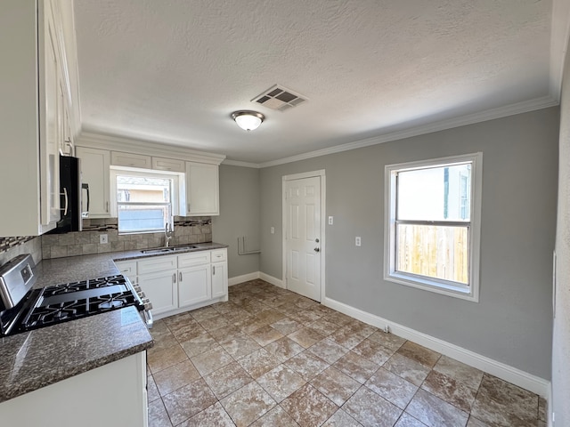 1013 E 40th St, Houston, TX 77022 - kitchen with gas stove, tasteful backsplash, ornamental molding, white cabinetry, and a textured ceiling