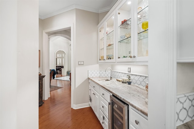 7417 Teaswood Dr, Conroe, TX 77304 - indoor bar with wine cooler, arched walkways, dark wood-style flooring, ornamental molding, and decorative backsplash