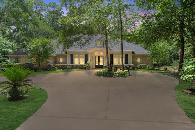 7417 Teaswood Dr, Conroe, TX 77304 - view of front facade featuring french doors, brick siding, and curved driveway