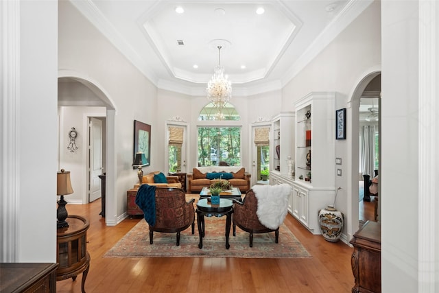 7417 Teaswood Dr, Conroe, TX 77304 - living room featuring arched walkways, light wood-type flooring, a chandelier, a raised ceiling, and recessed lighting