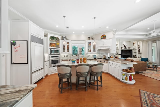 7417 Teaswood Dr, Conroe, TX 77304 - kitchen featuring built in appliances, a peninsula, open floor plan, white cabinets, and backsplash