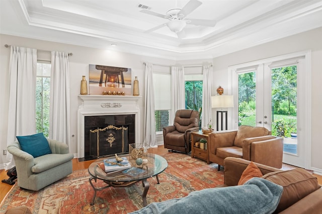 7417 Teaswood Dr, Conroe, TX 77304 - living room featuring a tray ceiling, ornamental molding, a fireplace with flush hearth, wood finished floors, and ceiling fan