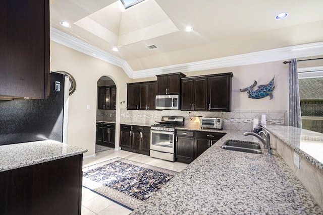 907 Fairway Dr, La Porte, TX 77571 - kitchen featuring stainless steel appliances, light tile patterned floors, light stone countertops, crown molding, and arched walkways