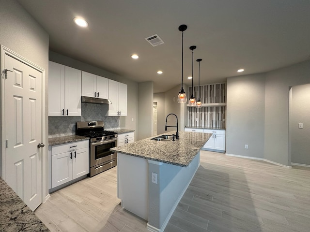 4215 Stuebner Hill Dr, Houston, TX 77068 - kitchen with stainless steel gas range oven, under cabinet range hood, light wood-type flooring, backsplash, and a center island with sink