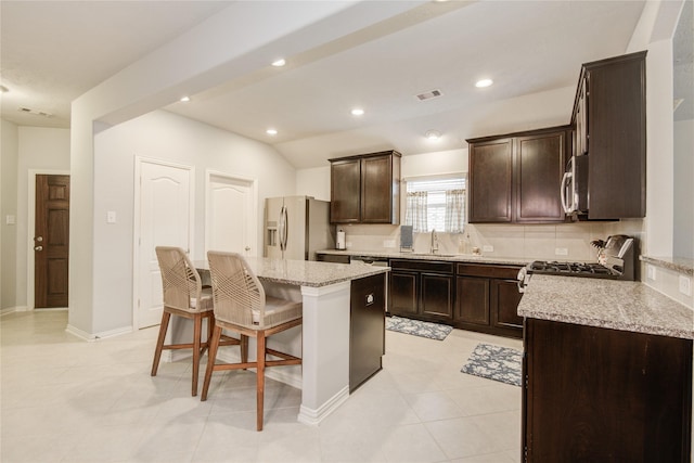 115 Meadow Ridge Way, Clute, TX 77531 - kitchen with appliances with stainless steel finishes, a breakfast bar area, a center island, dark brown cabinets, and light stone countertops