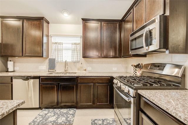 115 Meadow Ridge Way, Clute, TX 77531 - kitchen with appliances with stainless steel finishes, tasteful backsplash, dark brown cabinets, and light tile patterned floors
