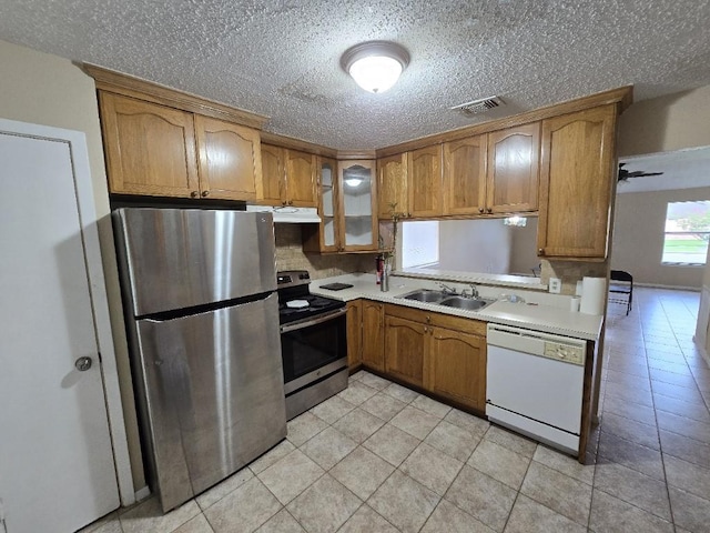 3902 Quiet Place Dr, Houston, TX 77082 - kitchen featuring appliances with stainless steel finishes, under cabinet range hood, light countertops, brown cabinetry, and a textured ceiling