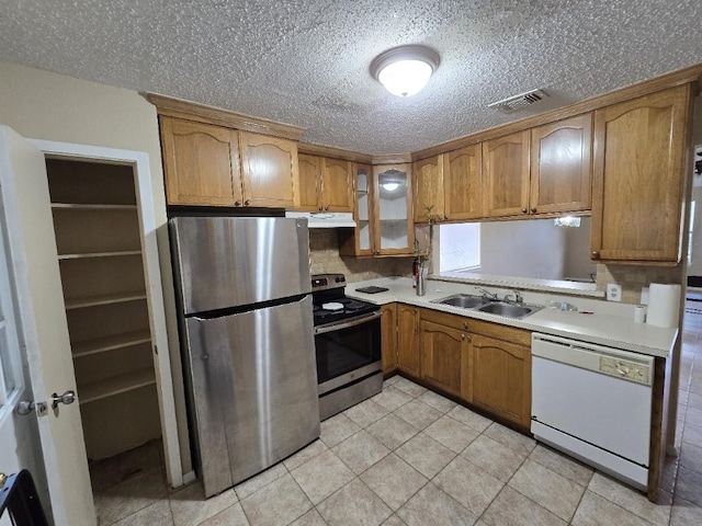 3902 Quiet Place Dr, Houston, TX 77082 - kitchen featuring appliances with stainless steel finishes, under cabinet range hood, light countertops, brown cabinets, and glass insert cabinets