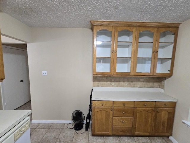 3902 Quiet Place Dr, Houston, TX 77082 - kitchen featuring light countertops, brown cabinets, glass insert cabinets, a textured ceiling, and dishwasher