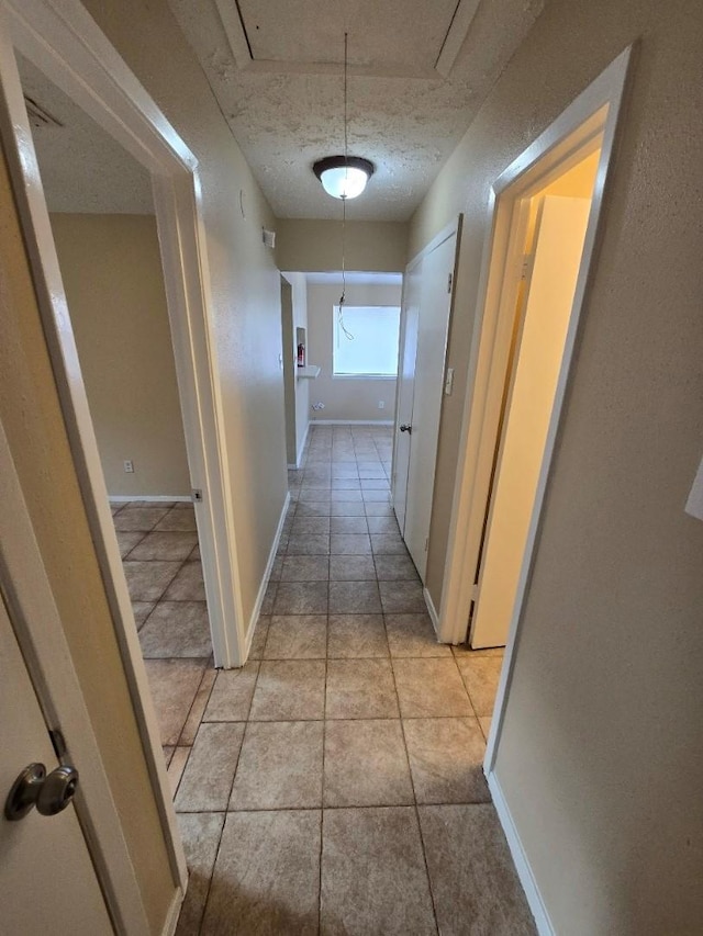 3902 Quiet Place Dr, Houston, TX 77082 - hallway with attic access, light tile patterned flooring, and a textured ceiling