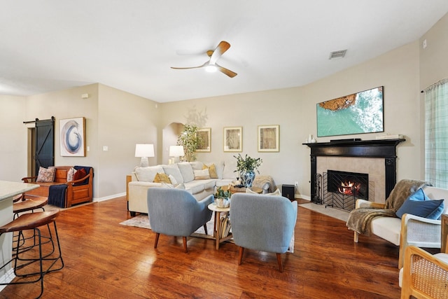 1095 Gladstone Dr, League City, TX 77573 - living area with wood-type flooring, ceiling fan, a fireplace, a barn door, and arched walkways