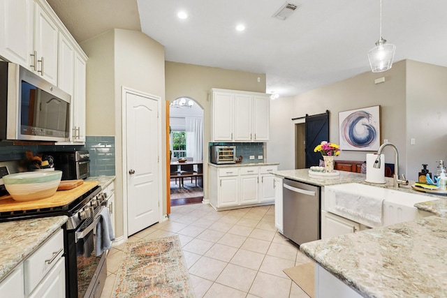 1095 Gladstone Dr, League City, TX 77573 - kitchen featuring appliances with stainless steel finishes, backsplash, white cabinetry, a barn door, and light tile patterned flooring