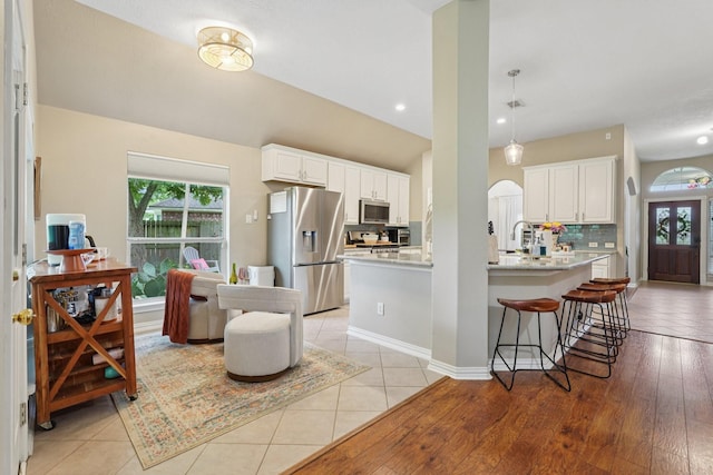 1095 Gladstone Dr, League City, TX 77573 - kitchen featuring stainless steel appliances, light countertops, backsplash, white cabinets, and a kitchen bar