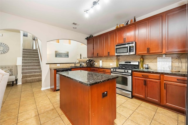 9859 Clanton Pines Dr, Humble, TX 77396 - kitchen featuring appliances with stainless steel finishes, a center island, arched walkways, and light tile patterned flooring