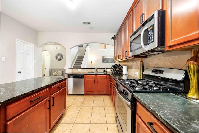 9859 Clanton Pines Dr, Humble, TX 77396 - kitchen with appliances with stainless steel finishes, arched walkways, decorative backsplash, and dark stone counters