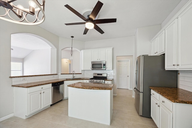 20703 Surrey Stone Ct, Katy, TX 77450 - kitchen with appliances with stainless steel finishes, arched walkways, backsplash, a center island, and a ceiling fan