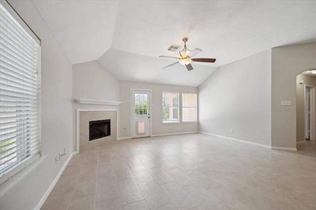 20703 Surrey Stone Ct, Katy, TX 77450 - unfurnished living room featuring a ceiling fan, lofted ceiling, a tile fireplace, arched walkways, and light tile patterned flooring