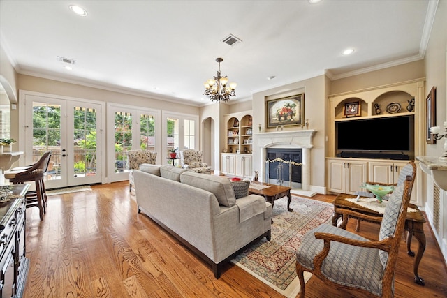8518 Prichett Dr, Houston, TX 77096 - living room featuring ornamental molding, a glass covered fireplace, a chandelier, built in shelves, and french doors