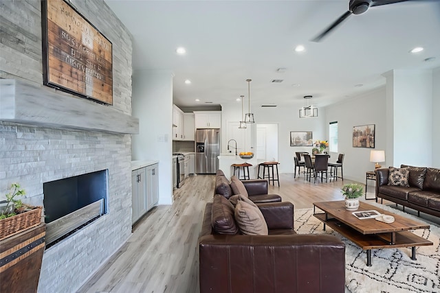 3323 Cornell St, Houston, TX 77022 - living area with light wood finished floors, recessed lighting, a fireplace, a ceiling fan, and crown molding