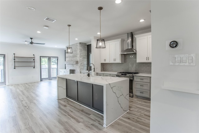 3323 Cornell St, Houston, TX 77022 - kitchen with wall chimney exhaust hood, gas range, open floor plan, decorative backsplash, and a ceiling fan