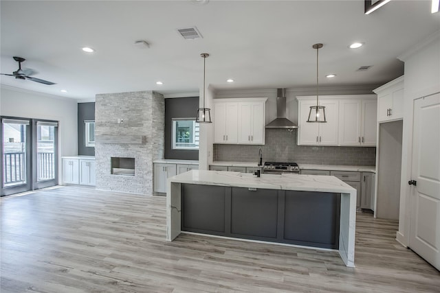 3323 Cornell St, Houston, TX 77022 - kitchen with wall chimney range hood, ornamental molding, stainless steel gas range, healthy amount of natural light, and ceiling fan