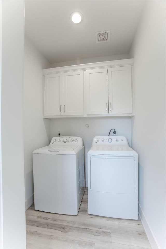 3323 Cornell St, Houston, TX 77022 - washroom featuring washer and clothes dryer, cabinet space, and light wood-style floors