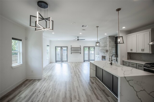 3323 Cornell St, Houston, TX 77022 - kitchen featuring open floor plan, light stone countertops, light wood-type flooring, backsplash, and ornamental molding