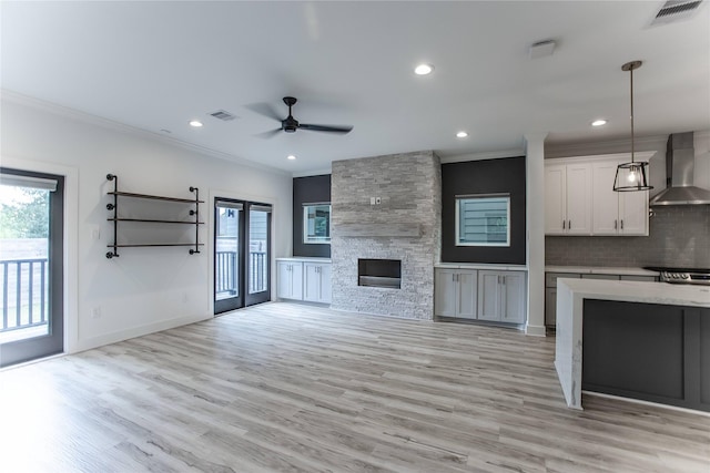 3323 Cornell St, Houston, TX 77022 - kitchen featuring wall chimney range hood, ornamental molding, open floor plan, plenty of natural light, and light countertops