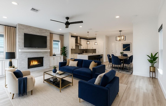 3323 Cornell St, Houston, TX 77022 - living area with light wood-type flooring, ceiling fan, a chandelier, a fireplace, and recessed lighting
