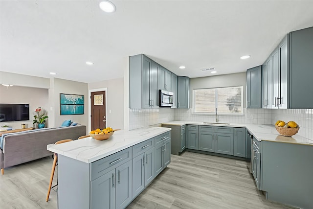 6315 Dellfern Dr, Houston, TX 77035 - kitchen featuring stainless steel appliances, open floor plan, light stone counters, a kitchen breakfast bar, and backsplash