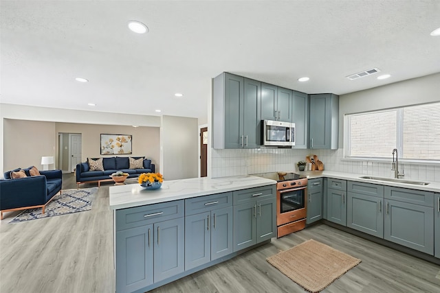 6315 Dellfern Dr, Houston, TX 77035 - kitchen featuring stainless steel appliances, light wood-type flooring, decorative backsplash, a peninsula, and recessed lighting