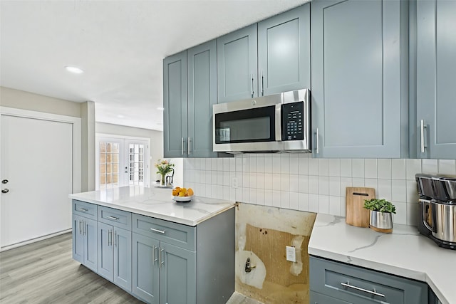 6315 Dellfern Dr, Houston, TX 77035 - kitchen with stainless steel microwave, light wood-style flooring, tasteful backsplash, light stone countertops, and gray cabinets