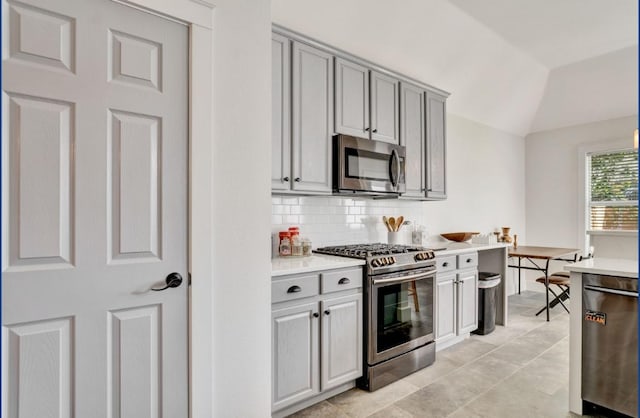3115 Sable Xing, San Antonio, TX 78232 - kitchen with stainless steel appliances, gray cabinetry, decorative backsplash, light countertops, and lofted ceiling