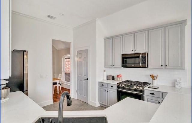 3115 Sable Xing, San Antonio, TX 78232 - kitchen with stainless steel appliances, light countertops, decorative backsplash, gray cabinetry, and crown molding