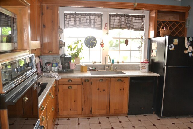 11014 Indian Trails Dr, Tomball, TX 77375 - kitchen featuring black appliances, light countertops, tasteful backsplash, brown cabinets, and light floors