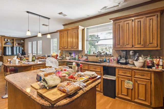 8414 Atascocita Lake Way, Humble, TX 77346 - kitchen featuring a kitchen island, light wood-style flooring, decorative backsplash, ornamental molding, and light stone countertops