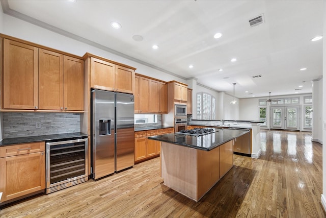709 Lester St, Houston, TX 77007 - kitchen featuring stainless steel appliances, beverage cooler, crown molding, a center island, and light wood-type flooring