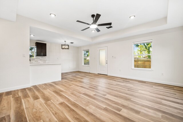 6321 Joe Louis Ln, Houston, TX 77091 - unfurnished living room featuring a chandelier, light wood finished floors, a ceiling fan, a tray ceiling, and recessed lighting