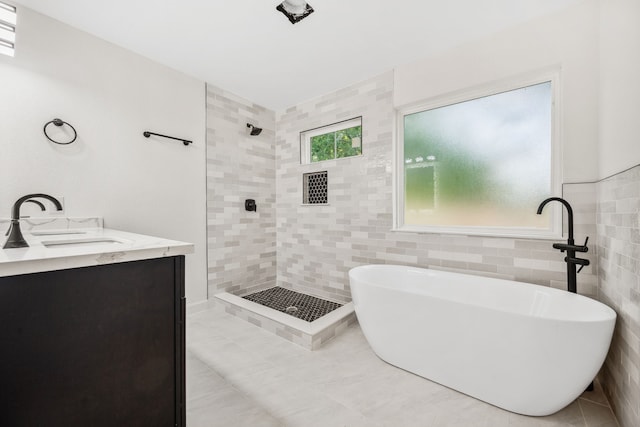 6321 Joe Louis Ln, Houston, TX 77091 - full bathroom featuring a freestanding bath, a tile shower, tile walls, tile patterned flooring, and double vanity