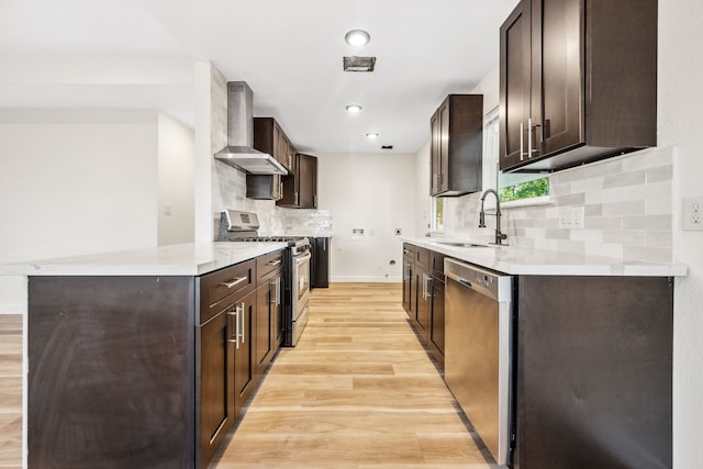 6321 Joe Louis Ln, Houston, TX 77091 - kitchen with stainless steel appliances, wall chimney exhaust hood, dark brown cabinets, light wood finished floors, and tasteful backsplash