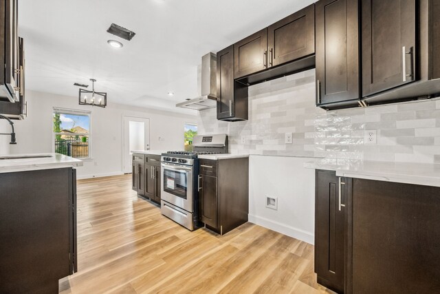 6321 Joe Louis Ln, Houston, TX 77091 - kitchen featuring stainless steel range with gas stovetop, wall chimney exhaust hood, dark brown cabinets, light wood-style flooring, and backsplash