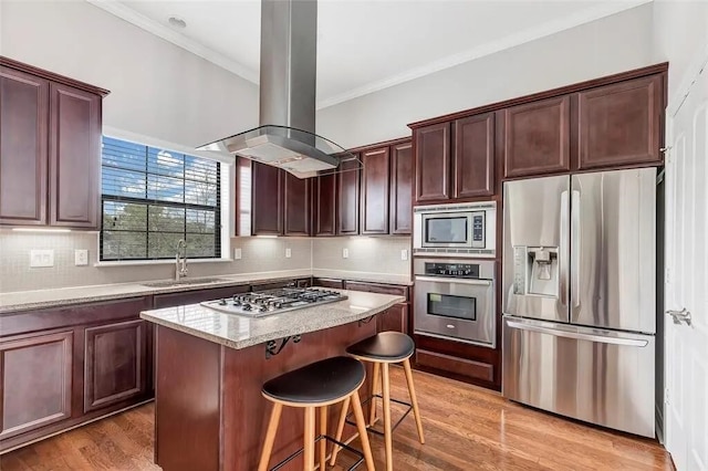 3204 Garden Oaks Vw, Houston, TX 77018 - kitchen featuring appliances with stainless steel finishes, island exhaust hood, ornamental molding, light wood-style flooring, and a center island