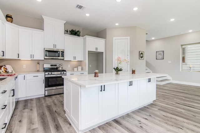 15034 Wunderlust Ln, Houston, TX 77069 - kitchen featuring appliances with stainless steel finishes, light wood-style floors, a kitchen island, white cabinetry, and recessed lighting
