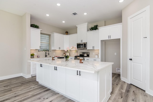 15034 Wunderlust Ln, Houston, TX 77069 - kitchen featuring stainless steel appliances, light wood-style floors, white cabinets, a center island, and recessed lighting