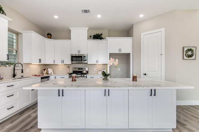 15034 Wunderlust Ln, Houston, TX 77069 - kitchen featuring stainless steel appliances, white cabinetry, light wood-type flooring, a large island, and recessed lighting